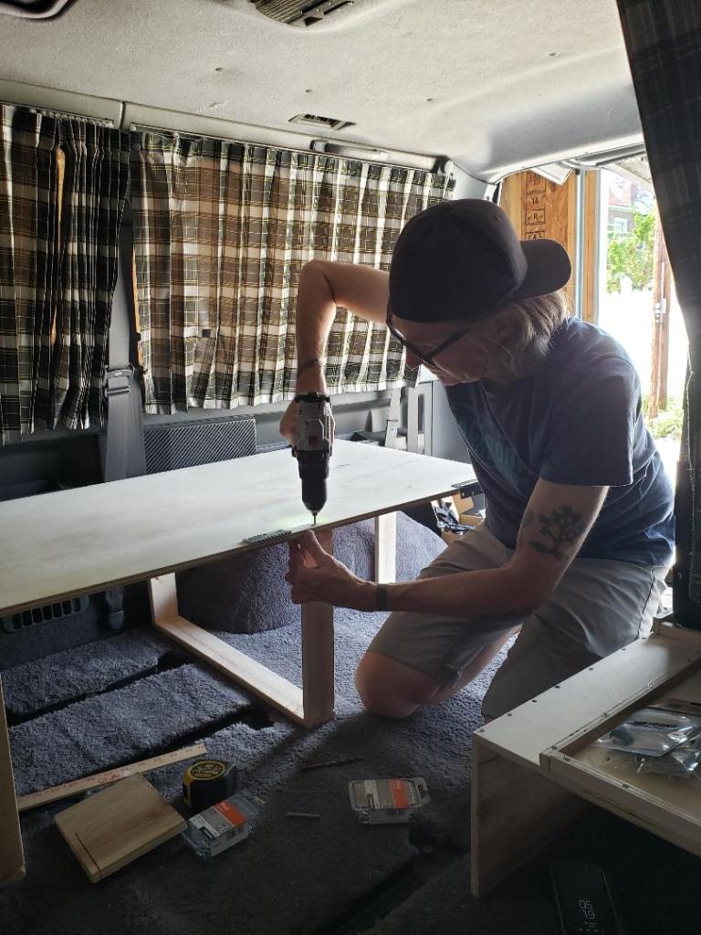 Mark drilling together a wooden bed in the van