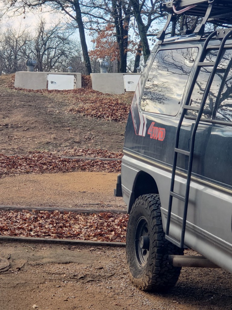 van parked in front of two storm shelters