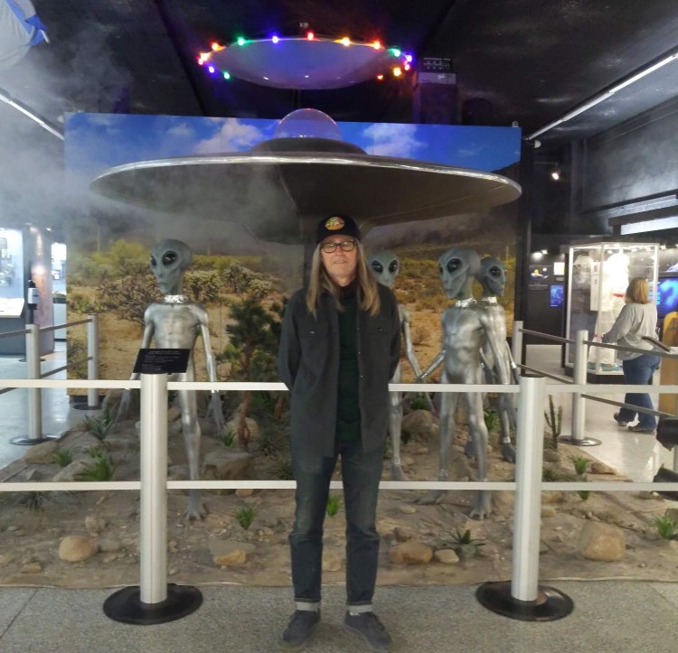 Mark standing in front a display with an UFO and aliens