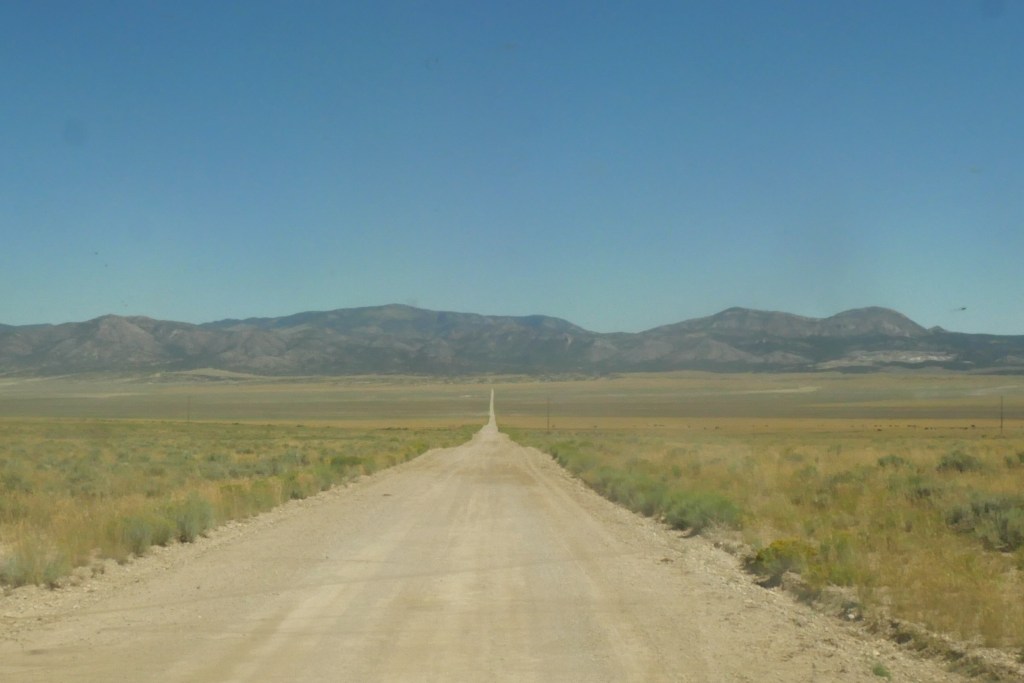 straight dirt road with mountains in the background